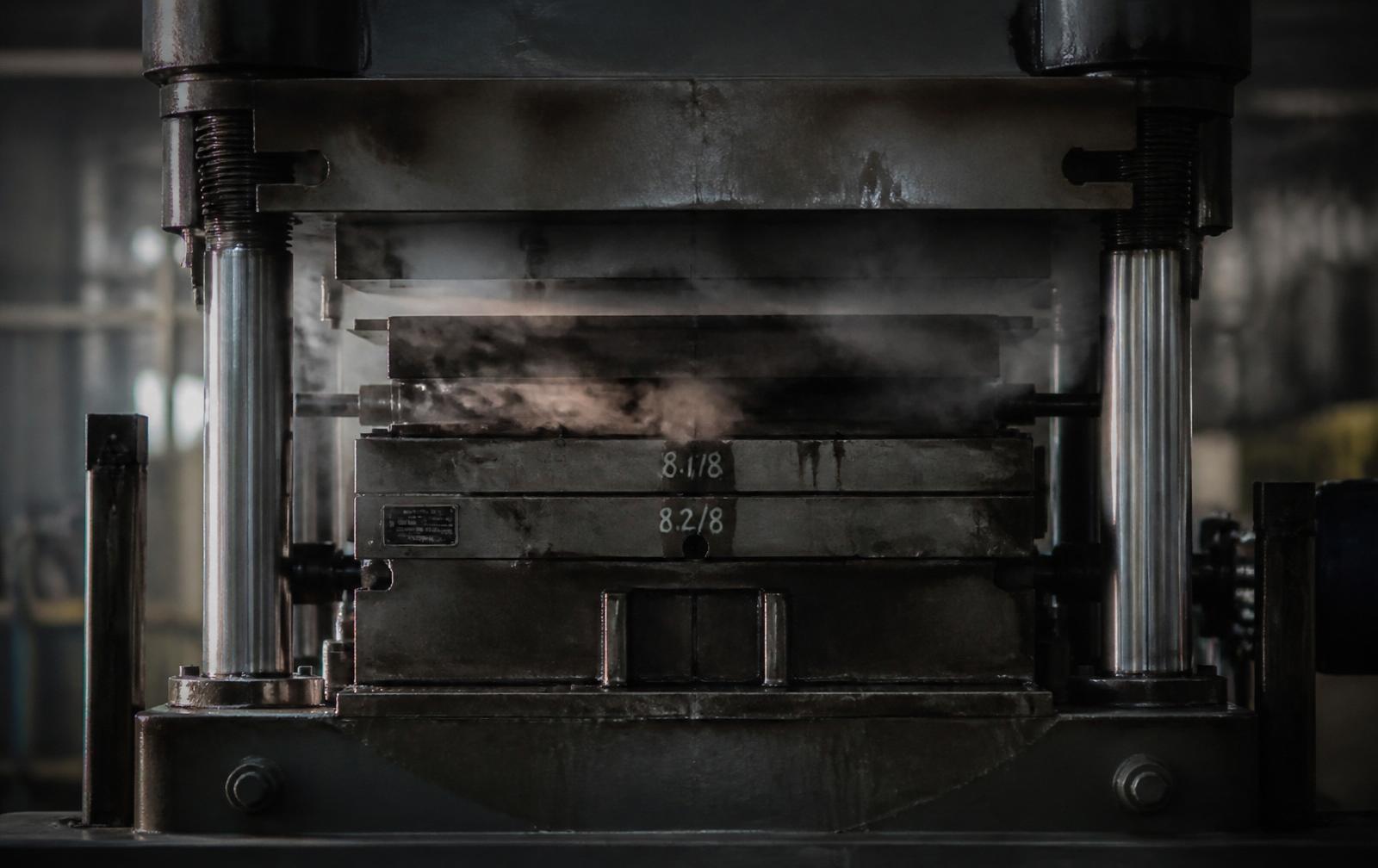 Hot rubber component being lifted from a compression moulding press